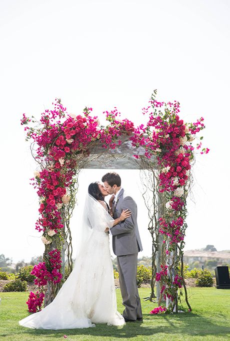 A romantic floral arbor covered in bright bougainvillea, fushia roses, and blush hydrangeas